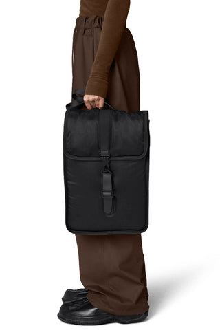 Model holding black RAINS Puffed Backpack Mini. 