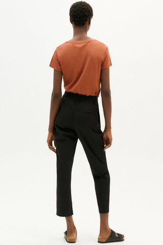 Back view of woman wearing black organic cotton carrot Rina Pants by Thinking Mu. 