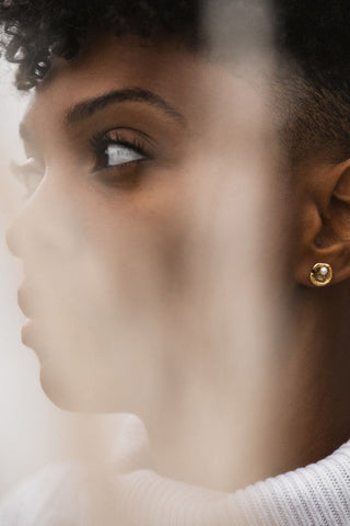 Model wearing Tilly Doro 24k gold plated and pearl Oyster stud earrings. 