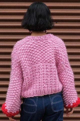 Back view of woman wearing pink and red chunky knit merino wool cardigan by Toast & Yam. 